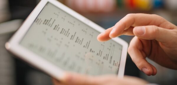 Mano interactuando con una tableta que muestra datos e información médica en pantalla.