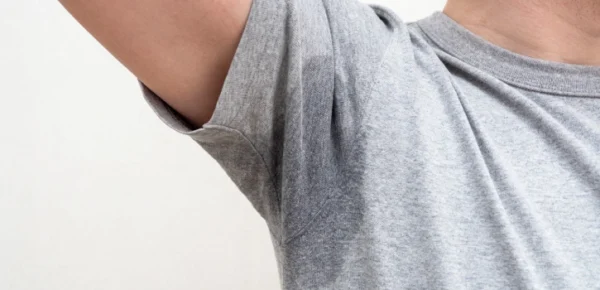 Mancha de sudor en la axila de una camiseta gris debido a hiperhidrosis